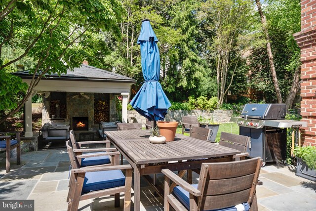 view of patio / terrace with a lit fireplace, outdoor dining area, and area for grilling