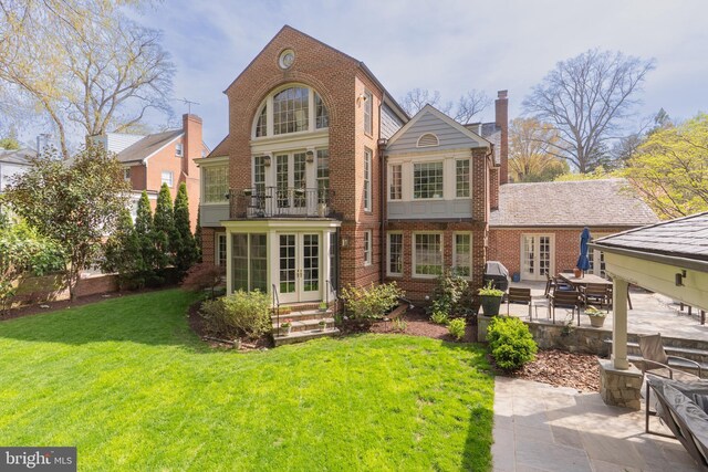 back of property with french doors, brick siding, a yard, and a patio area