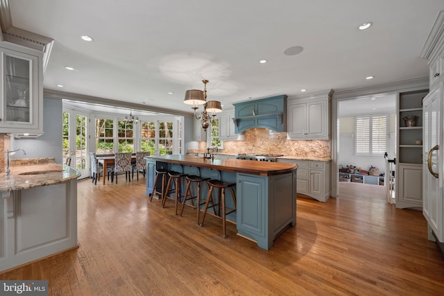 kitchen featuring a sink, premium range hood, wooden counters, light wood-style floors, and a chandelier
