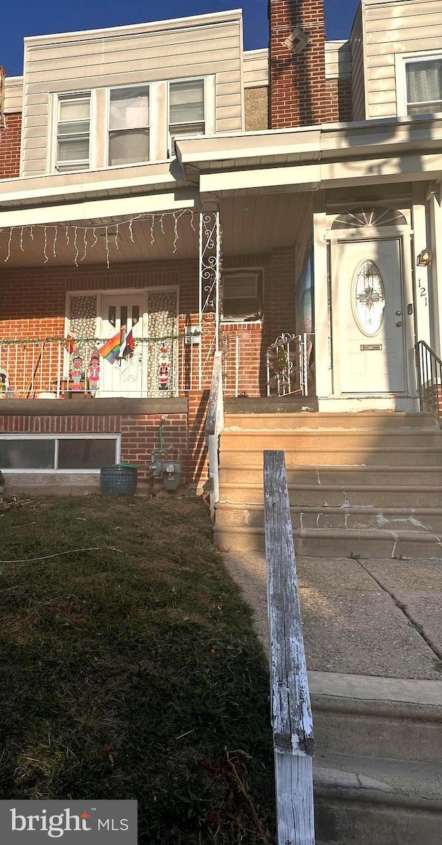 entrance to property with a porch and brick siding