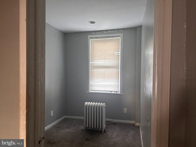 empty room with radiator, carpet floors, and baseboards