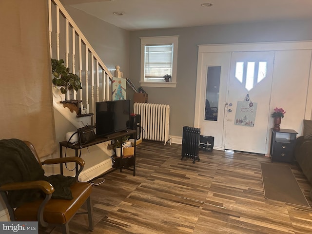 sitting room with radiator, wood finished floors, baseboards, and stairway