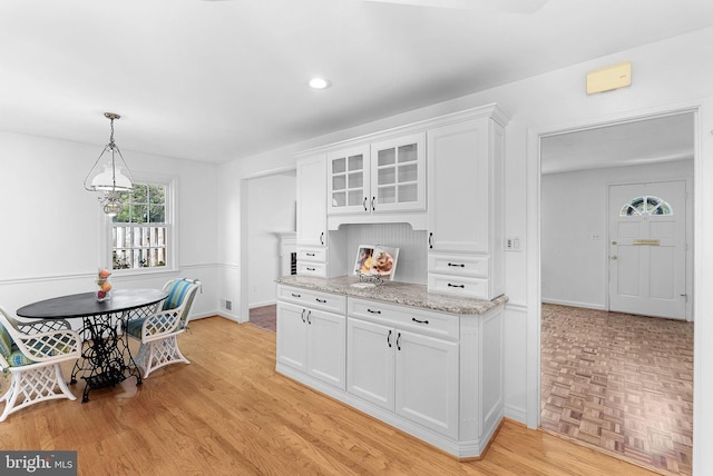 7607 Newcastle Dr, Annandale, VA 22003 - kitchen with white cabinets, light stone counters, glass insert cabinets, pendant lighting, and baseboards