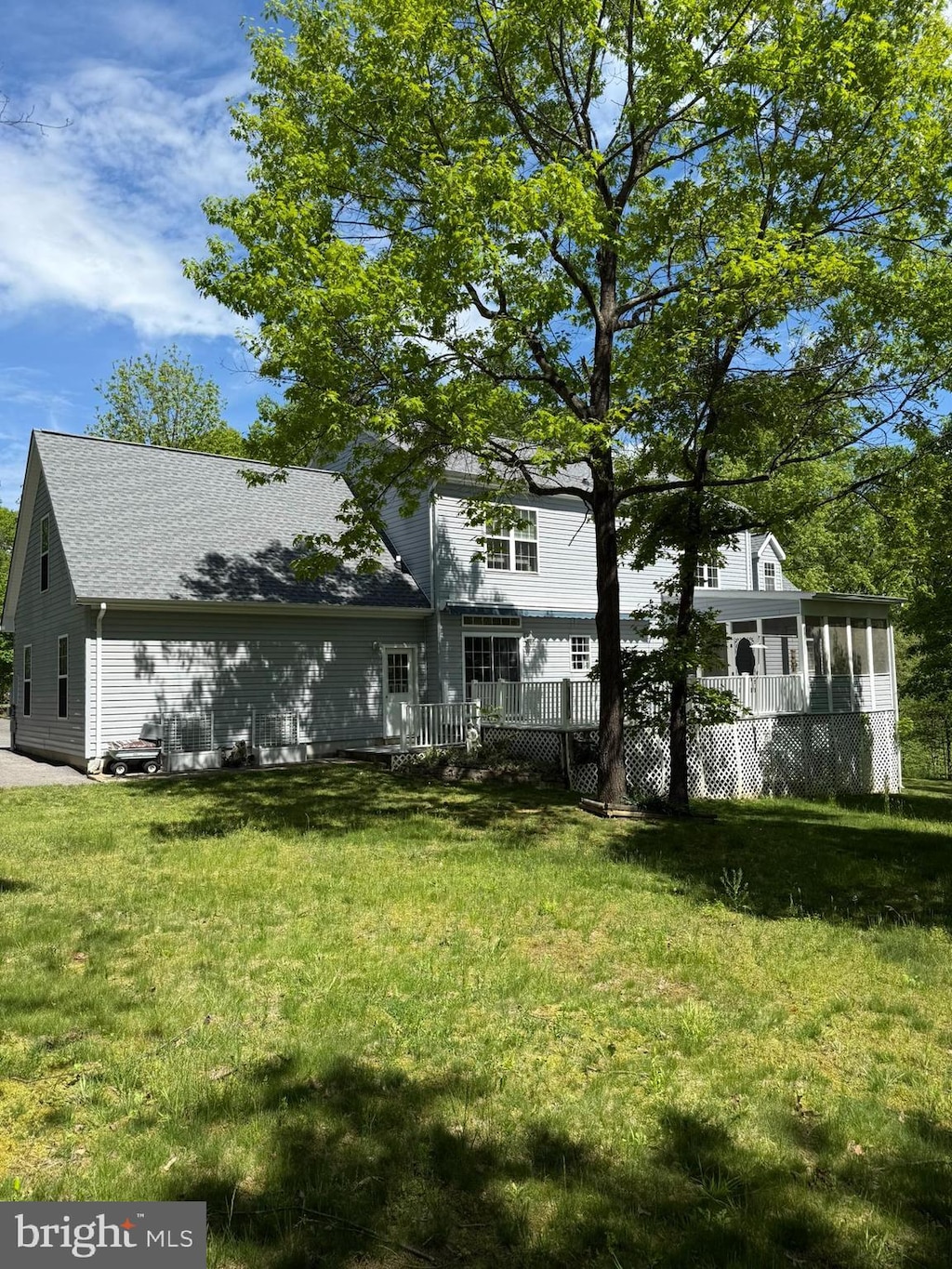 back of property featuring a yard, a sunroom, and a shingled roof