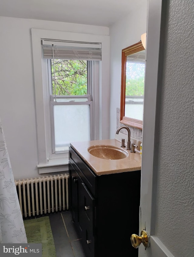 bathroom with radiator, healthy amount of natural light, vanity, and tile patterned flooring
