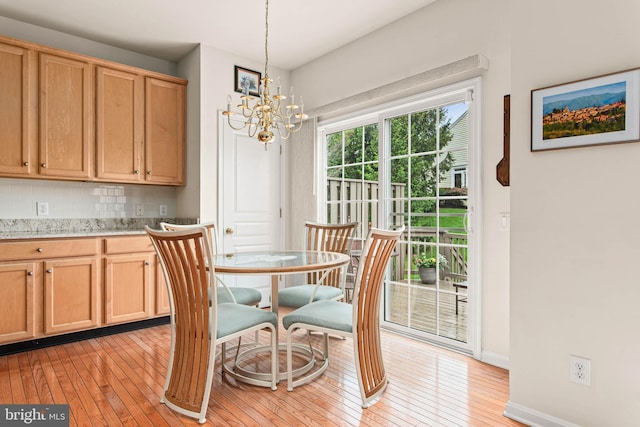dining space with light wood finished floors, a chandelier, and baseboards
