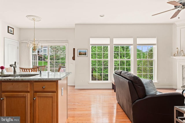 kitchen with a sink, a chandelier, light wood finished floors, a ceiling fan, and hanging light fixtures