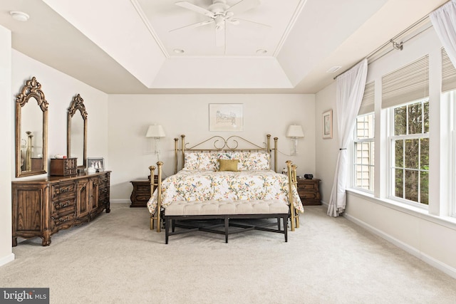 bedroom featuring a tray ceiling, light colored carpet, baseboards, and ceiling fan