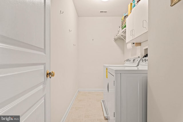 washroom featuring washing machine and dryer, cabinet space, baseboards, and light tile patterned floors