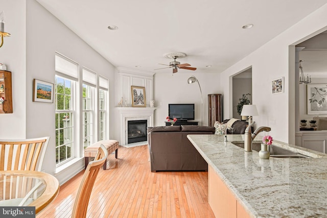living area with light wood-style floors, a fireplace with flush hearth, a ceiling fan, and recessed lighting
