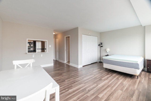 922 24th St NW Unit 806, Washington, DC 20037 - bedroom featuring freestanding refrigerator, wood finished floors, baseboards, and a closet