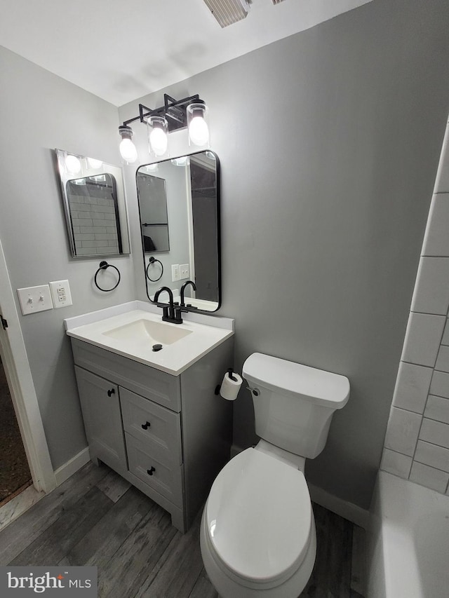 bathroom with wood finished floors, toilet, vanity, and baseboards