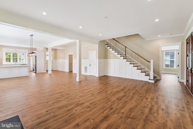 unfurnished living room with wood-type flooring, stairs, crown molding, a chandelier, and recessed lighting