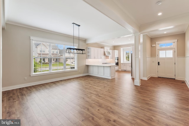 unfurnished living room with wood finished floors, crown molding, beamed ceiling, recessed lighting, and a chandelier