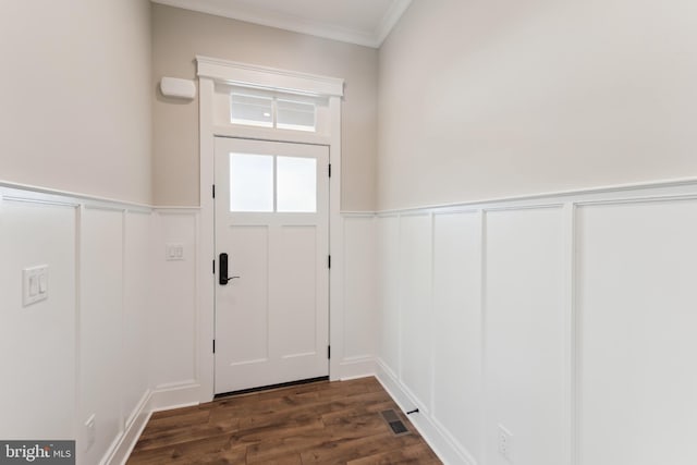 doorway to outside with ornamental molding, dark wood-style flooring, a decorative wall, and wainscoting