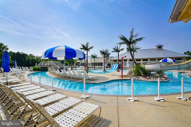 community pool featuring a water slide and a patio area