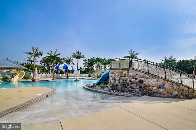 community pool featuring a water slide and a patio
