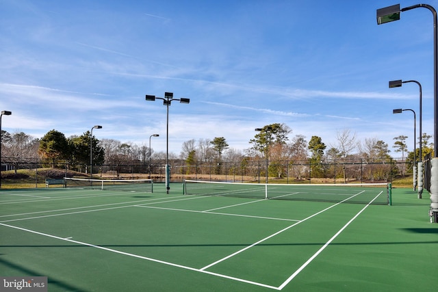 view of tennis court featuring community basketball court and fence