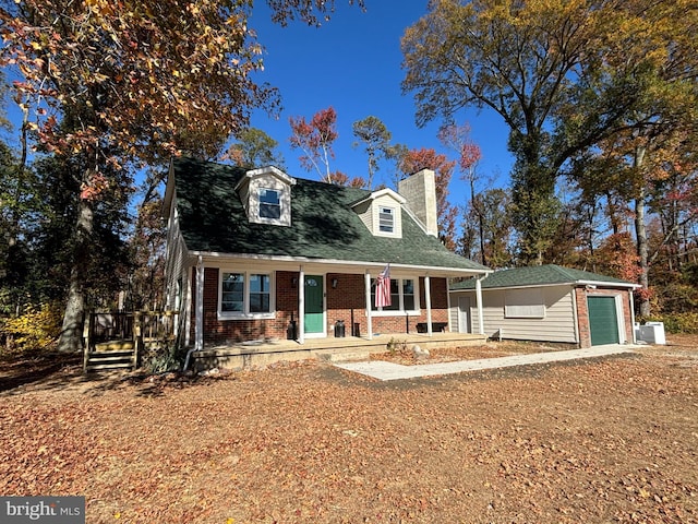 cape cod-style house featuring brick siding, a chimney, an outdoor structure, and covered porch
