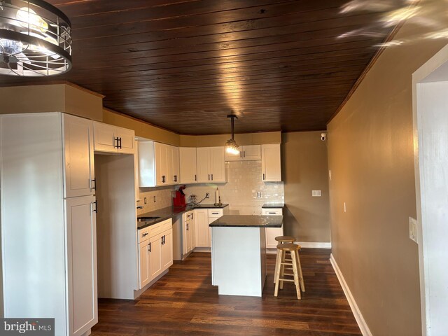 kitchen with wooden ceiling, dark countertops, dark wood finished floors, white cabinets, and decorative backsplash