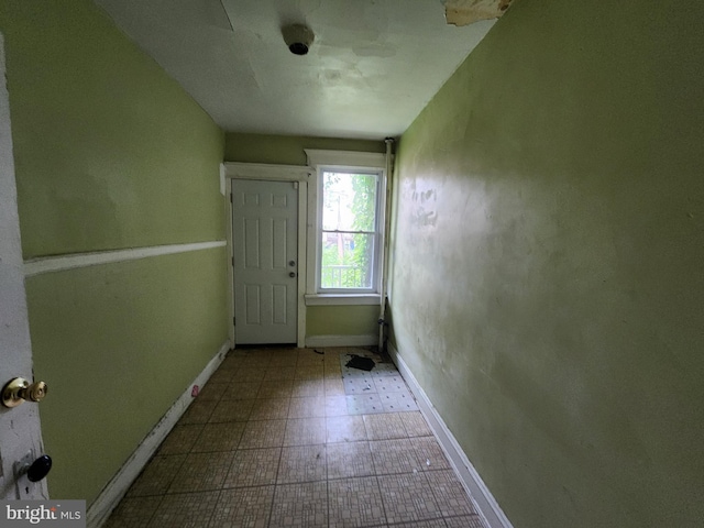 doorway with baseboards and tile patterned floors