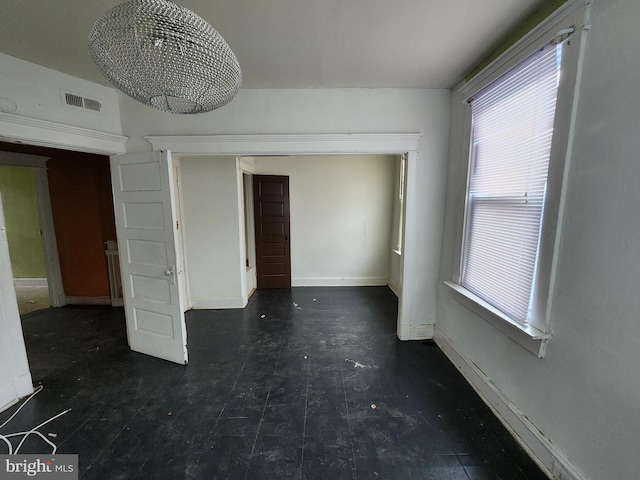 unfurnished room featuring plenty of natural light, a chandelier, and baseboards