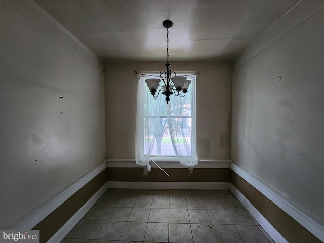 unfurnished dining area featuring a chandelier, light tile patterned floors, and baseboards