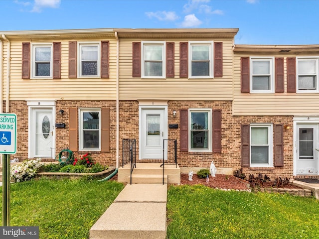 townhome / multi-family property with brick siding and a front yard