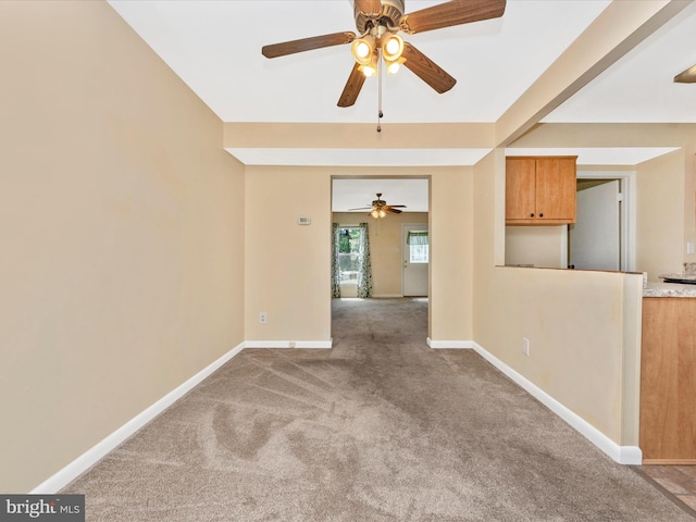 carpeted spare room featuring a ceiling fan and baseboards