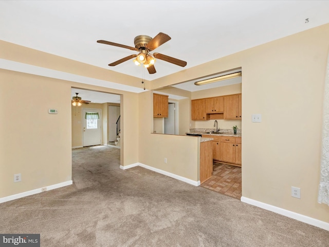 unfurnished living room featuring a sink, carpet, ceiling fan, baseboards, and stairway
