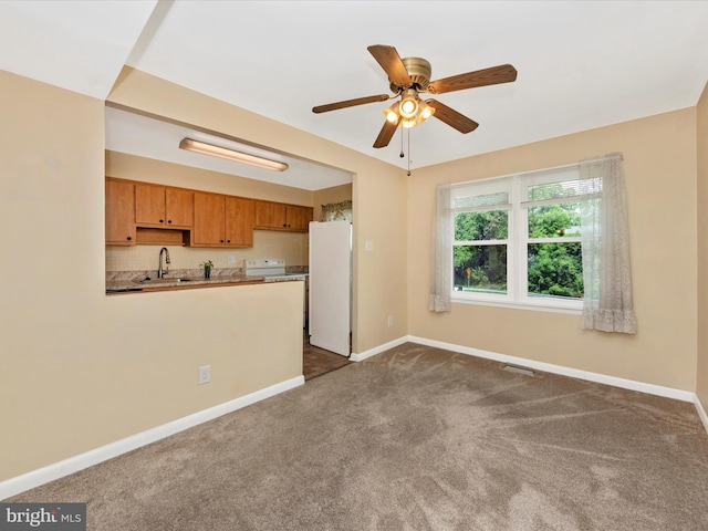 unfurnished living room with baseboards, dark colored carpet, a ceiling fan, and a sink