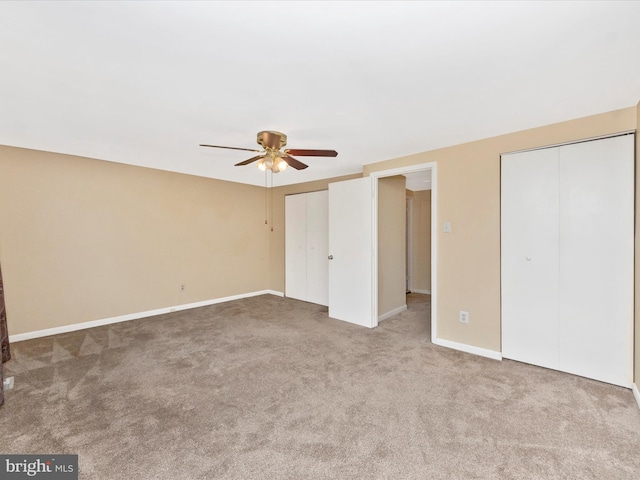 unfurnished bedroom with multiple closets, carpet, baseboards, and a ceiling fan