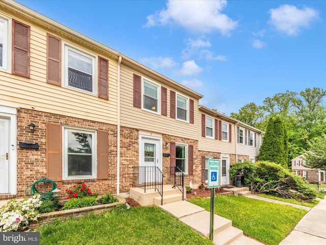 view of property with a front lawn and brick siding