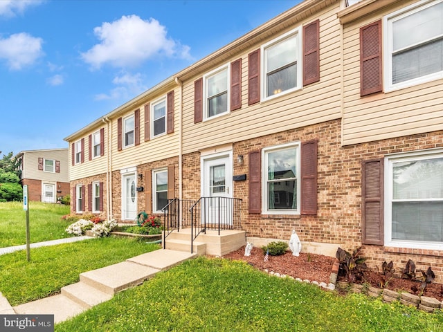 townhome / multi-family property featuring a front yard and brick siding