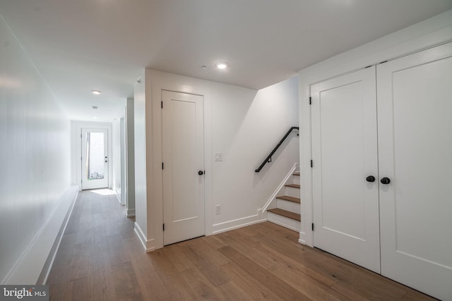 hall featuring wood finished floors, baseboards, stairs, and recessed lighting