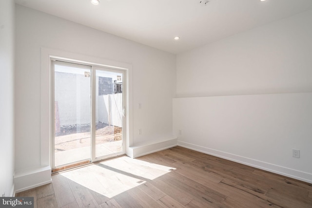 unfurnished room with wood finished floors, baseboards, and recessed lighting