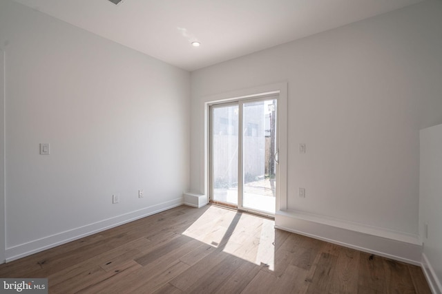 empty room featuring wood finished floors, baseboards, and recessed lighting
