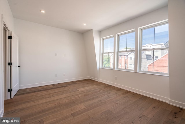 spare room with hardwood / wood-style floors, healthy amount of natural light, baseboards, and recessed lighting