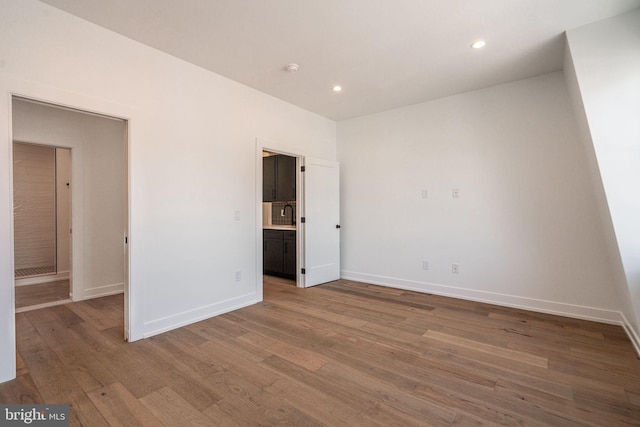 unfurnished bedroom with wood finished floors, baseboards, recessed lighting, and ensuite bath