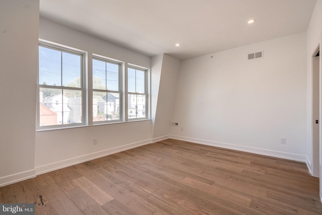empty room featuring wood finished floors, baseboards, and recessed lighting