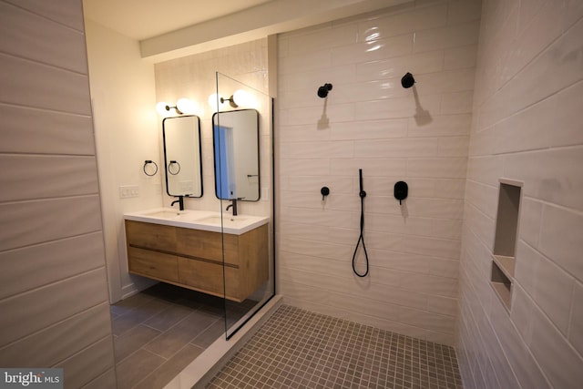bathroom with a tile shower, double vanity, and tile patterned floors
