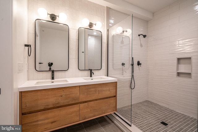 full bath with tiled shower, tile patterned floors, and double vanity