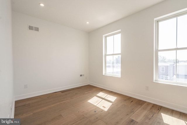 empty room featuring wood finished floors, baseboards, and recessed lighting