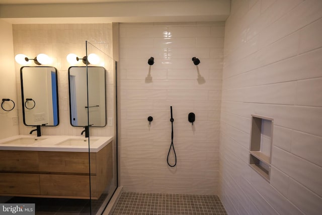 bathroom with a tile shower, double vanity, and tile patterned floors