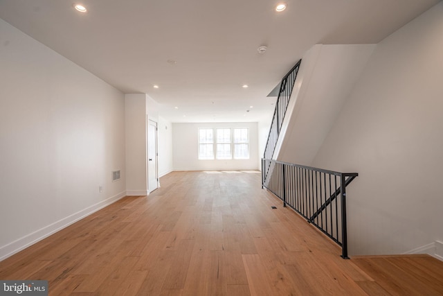 corridor with baseboards, light wood-type flooring, an upstairs landing, and recessed lighting