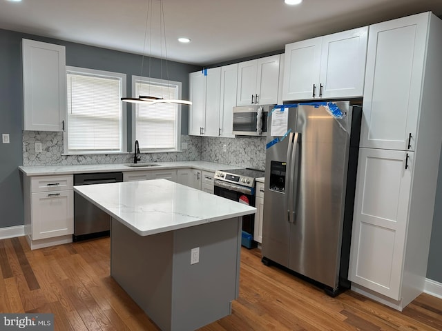 124 E Ruscomb St, Philadelphia, PA 19120 - kitchen with appliances with stainless steel finishes, a sink, wood finished floors, a kitchen island, and backsplash