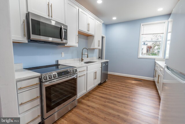 3211 Baker St, Baltimore, MD 21216 - kitchen with stainless steel appliances, a sink, light countertops, wood finished floors, and white cabinetry