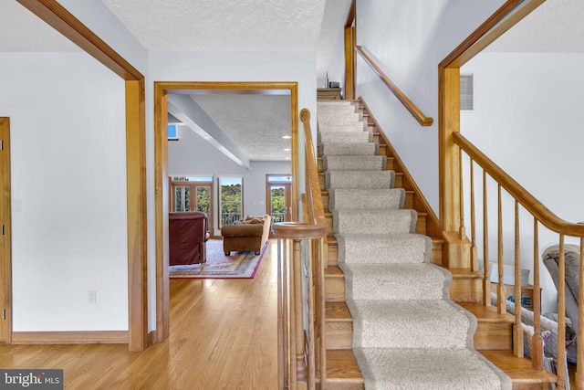 10150 Lapworth Pl, Charlotte Hall, MD 20622 - stairway featuring a textured ceiling, wood finished floors, and baseboards