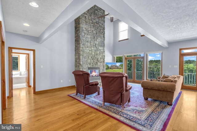 10150 Lapworth Pl, Charlotte Hall, MD 20622 - living area with a textured ceiling, light wood finished floors, a stone fireplace, and baseboards