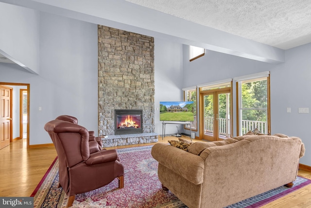 10150 Lapworth Pl, Charlotte Hall, MD 20622 - living room with light wood-type flooring, baseboards, a stone fireplace, a textured ceiling, and high vaulted ceiling
